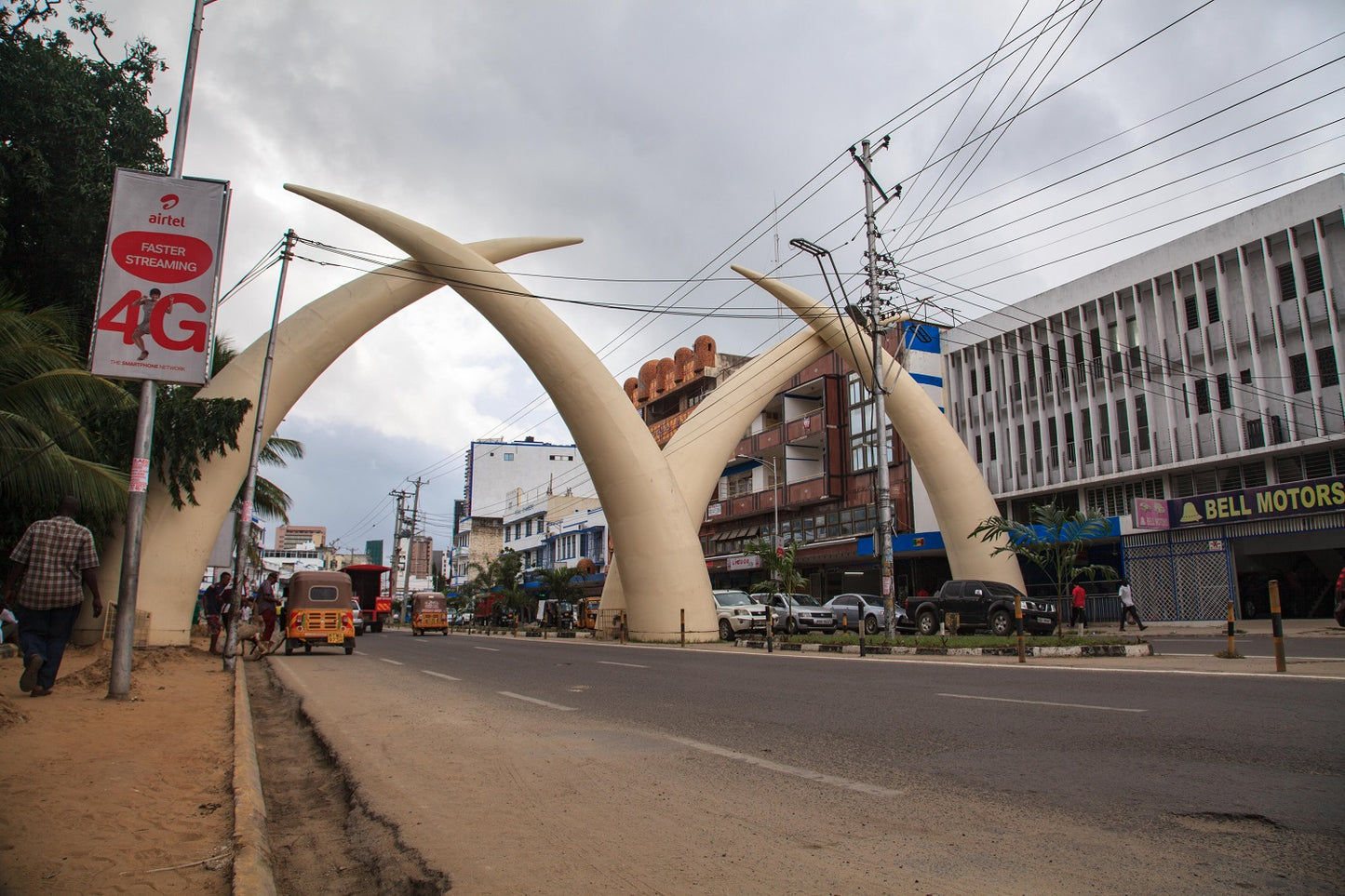 Street scene with large white metal tusk arches in an urban setting.