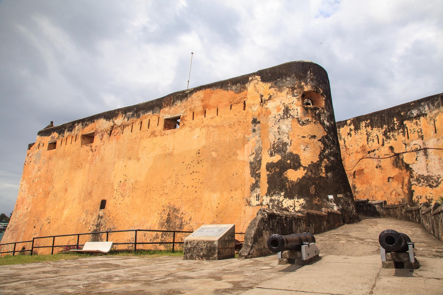 Old fort with two canons at the entrance with a slightly cloudy sky.