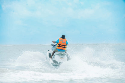 Person riding a jet ski on a body of water with a clear blue sky.