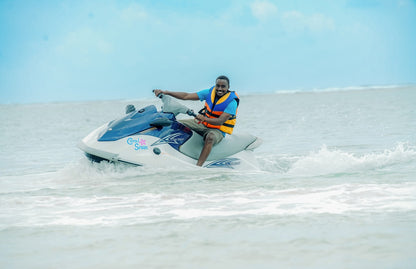 Person riding a jet ski on a clear day with blue sky and ocean.